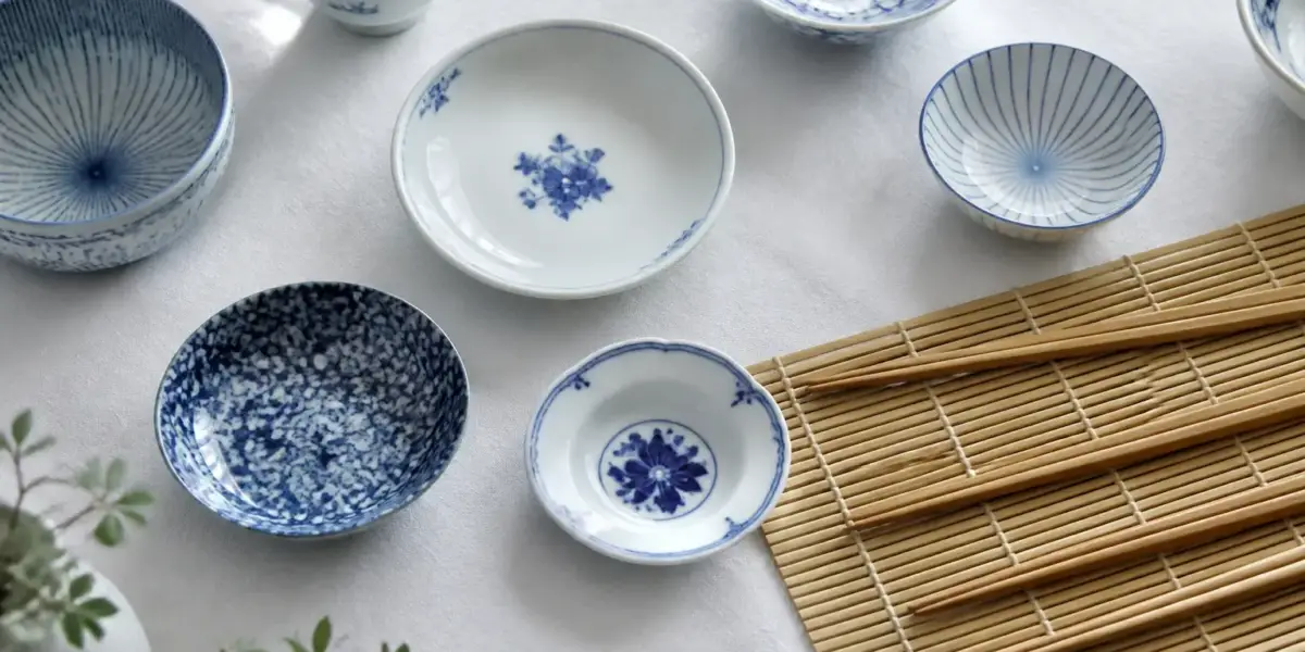 Vue de dessus d’une table dressée de coupelles bleu et blanc et de baguettes alignées