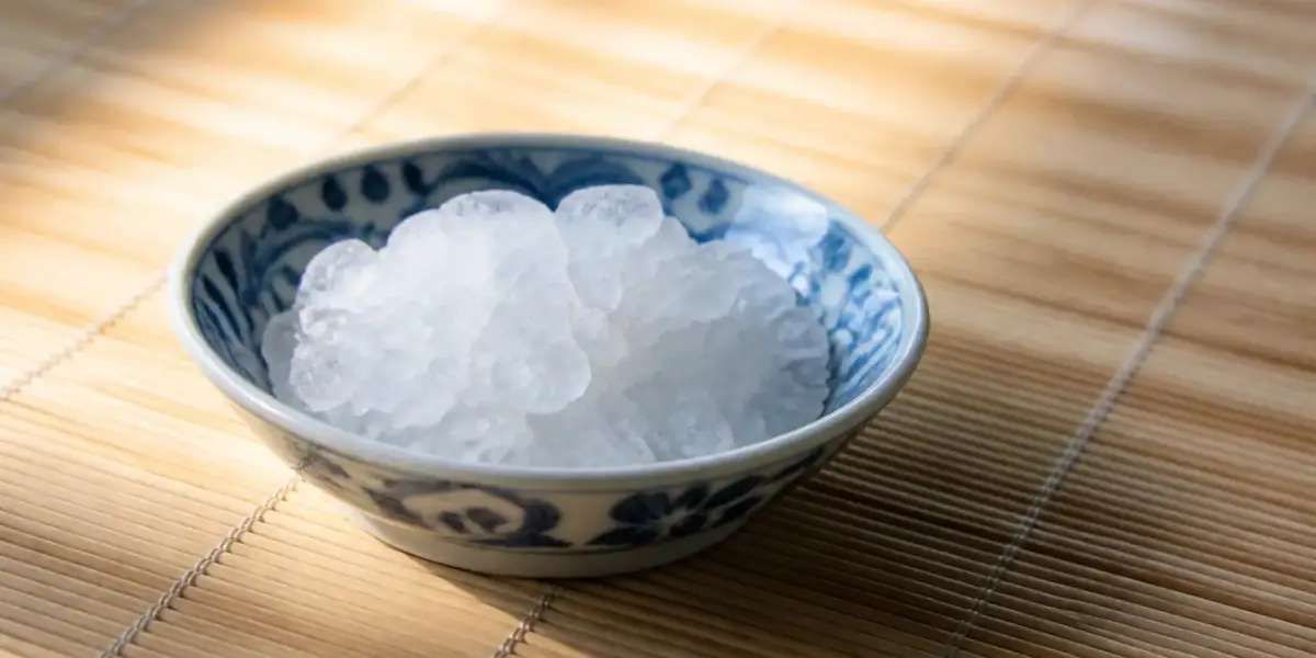 Petits cristaux blancs de glutamate monosodique dans une coupelle en porcelaine bleu et blanc