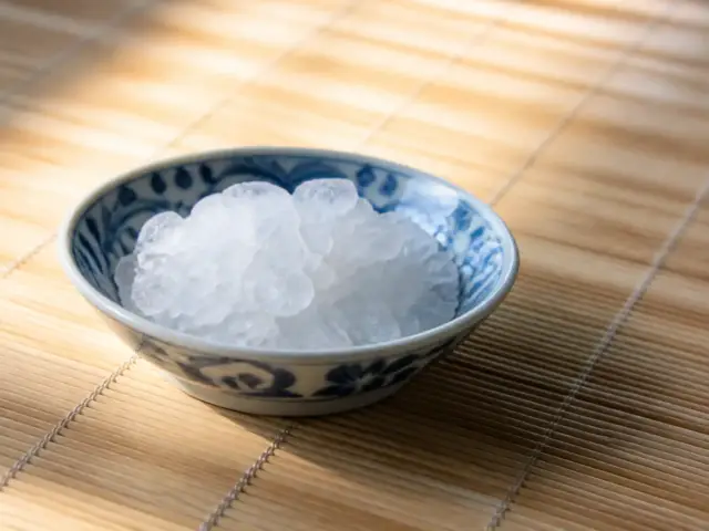 Petits cristaux blancs de glutamate monosodique dans une coupelle en porcelaine bleu et blanc