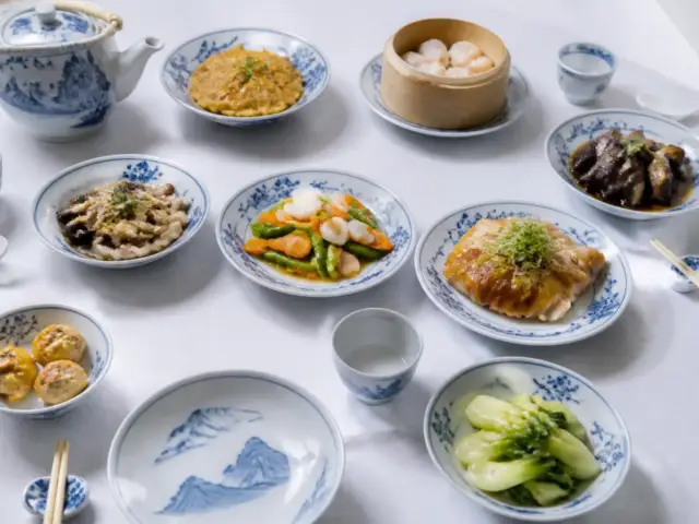 Table dressée de petits plats asiatiques variés dans des bols en porcelaine bleu et blanc, avec baguettes et théière