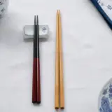 Deux paires de baguettes posées côte à côte, une japonaise laquée à pointe fine et une chinoise plus longue en bambou