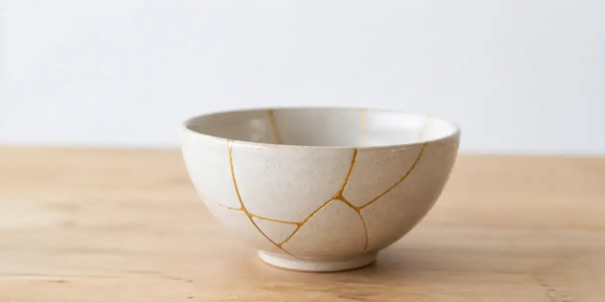 Bol en céramique beige réparé au kintsugi, ses fissures recouvertes de fines lignes dorées